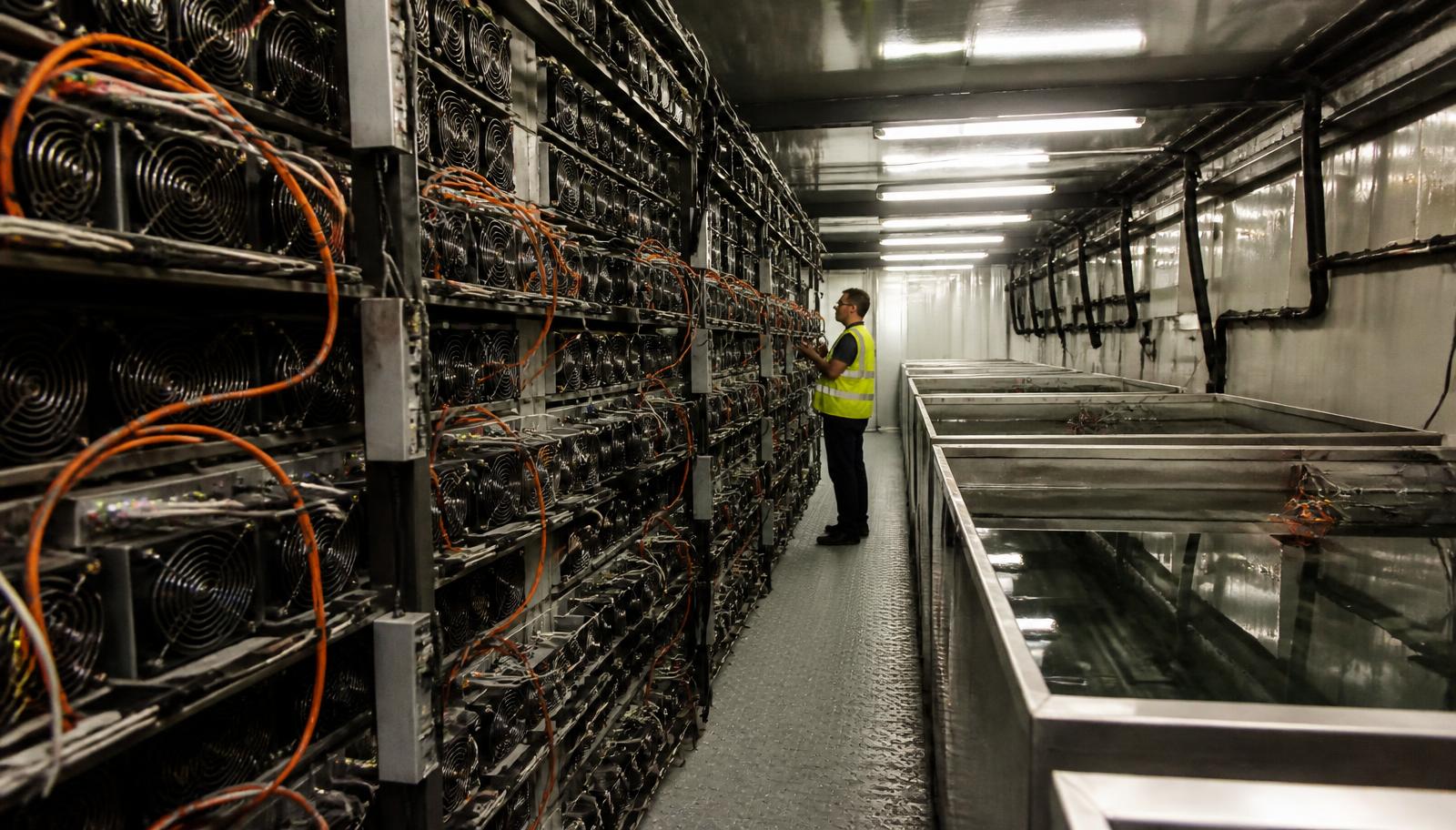 Interior de contêiner de mineração de bitcoin com racks de ASICs e tanques de imersão